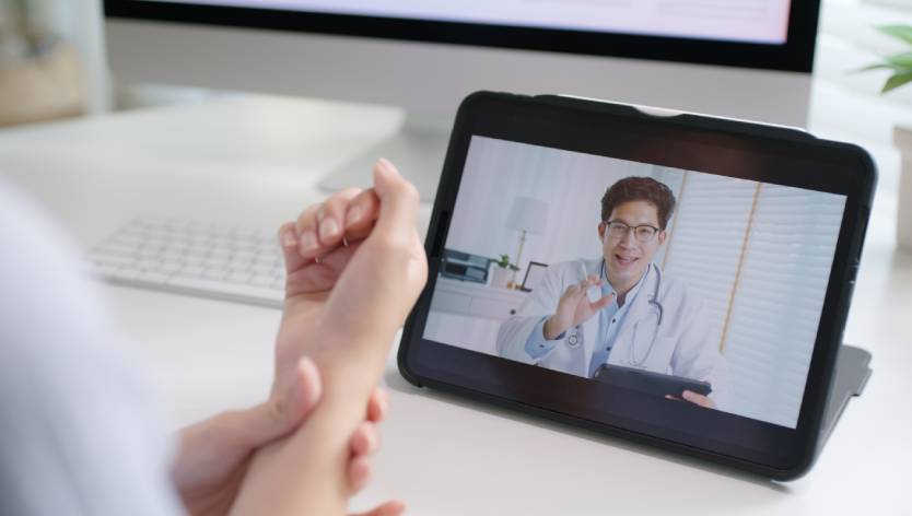 woman holding wrist talking to virtual doctor